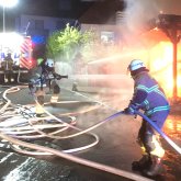 Feuerwehrmann mit Schlauch zum löschen eines Gebäudebrandes Zwei Feuerwehrmänner