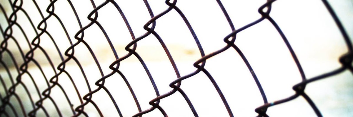 Ein Maschendrahtzaun als Symbolbild für Barriere Der Zaun als Barriere