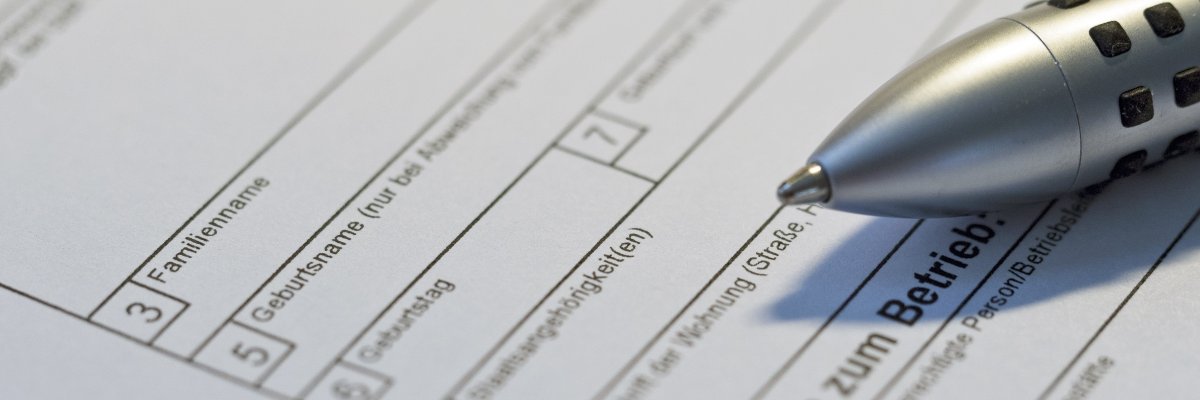 Auf einem Formular liegt ein grauer Kugelschreiber