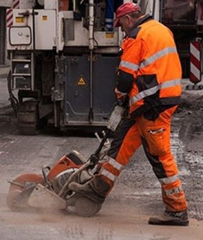 Ein Arbeiter in Arbeitskleidung mit einem lärmenden Gerät