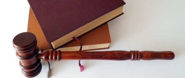 Zwei Bücher mit einem Hammer vor weißem Hindergrund