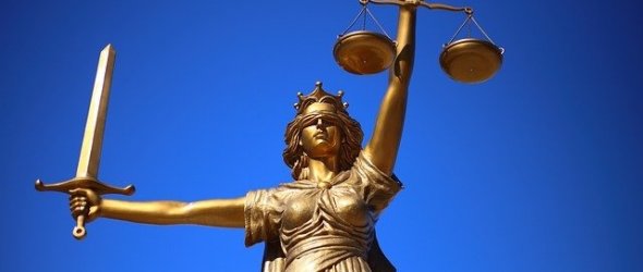 Skulptur der Gerechtigkeit die ein Schwert und eine Wage hochhält